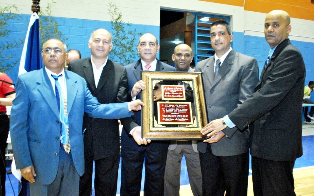 Los directivos de ASOBAE y el Comité Organizador entregan la placa de la dedicatoria de la justa al presidente del INDOTEL, el Lic. Carlos Amarante Baret siendo recibida por el Lic. Víctor Veras